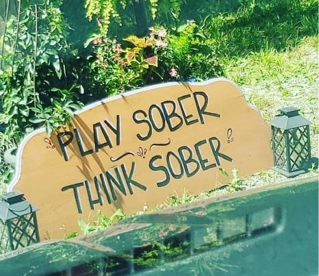 Play Sober, Think Sober painted on a wooden sign.
